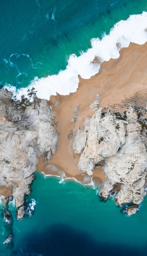 Aerial of Cabo San Lucas rocky coast meeting turquoise Pacific water