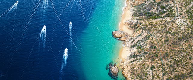 Aerial view of speedboats on deep blue water along the Baja California coastline
